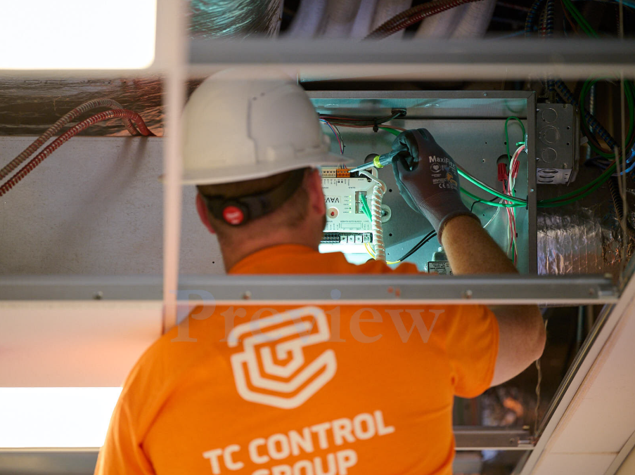 TC Controls technician installing a VAV controller in an above-ceiling plenum